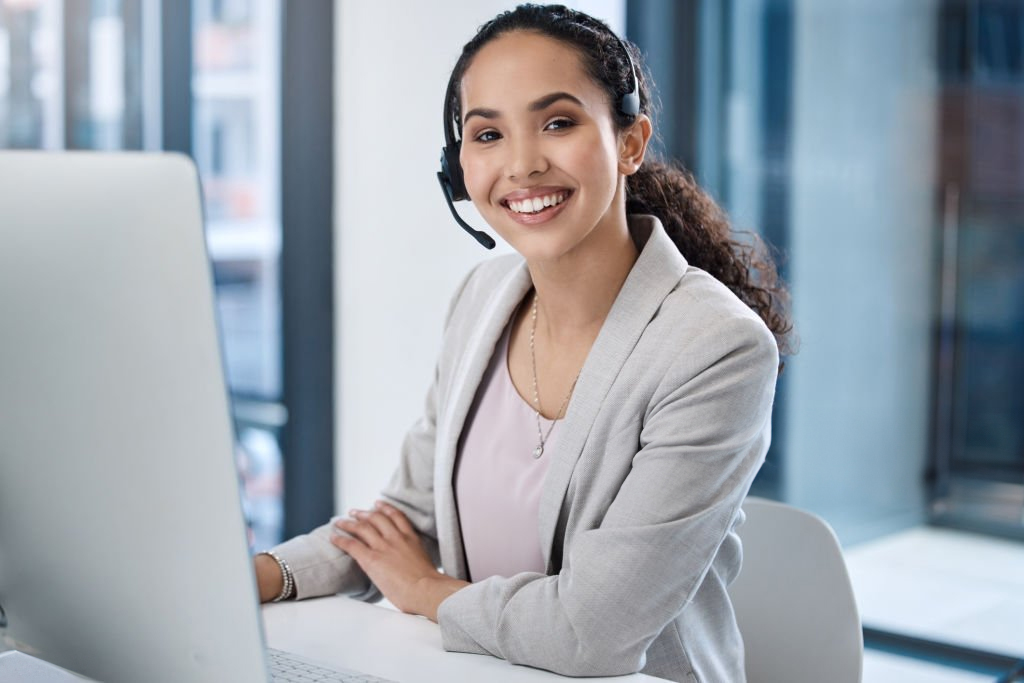 Smiling customer support representative wearing a headset at her desk.